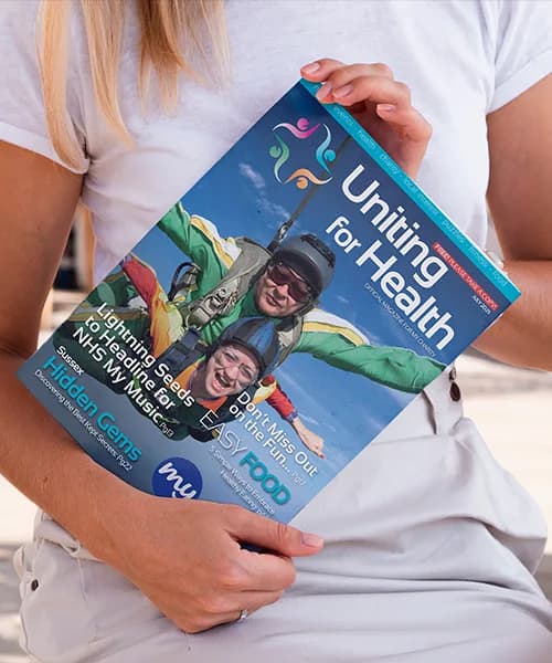 A reader holding the Uniting For Health magazine